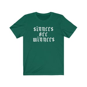May include: A green t-shirt with white text that reads "sinners are winners" in a gothic font.