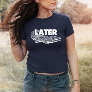 May include: A navy blue t-shirt with a white alligator graphic and the word "LATER" printed in white.
