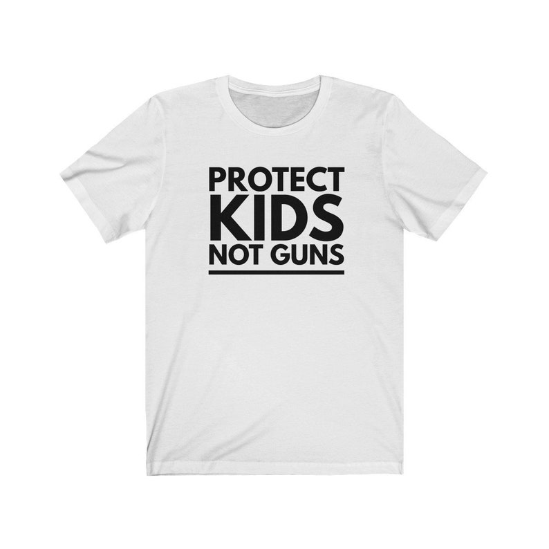 May include: White t-shirt with black text that reads "PROTECT KIDS NOT GUNS".