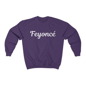 K&ouml;nnte beinhalten: Lilafarbener Pullover mit dem Wort "Feyonc&eacute;" in wei&szlig;er kursivschrift.