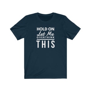 May include: A navy blue t-shirt with white text that reads "Hold on Let Me Overthink This".