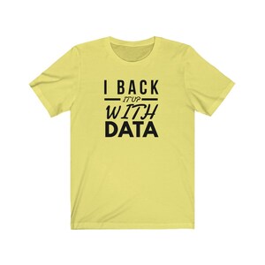 Puede incluir: Una camiseta de manga corta de color amarillo claro con texto negro centrado en el pecho que dice I BACK IT UP WITH DATA, con las palabras I BACK y DATA en una fuente sans-serif negrita y las palabras IT UP en una fuente m&aacute;s fina.