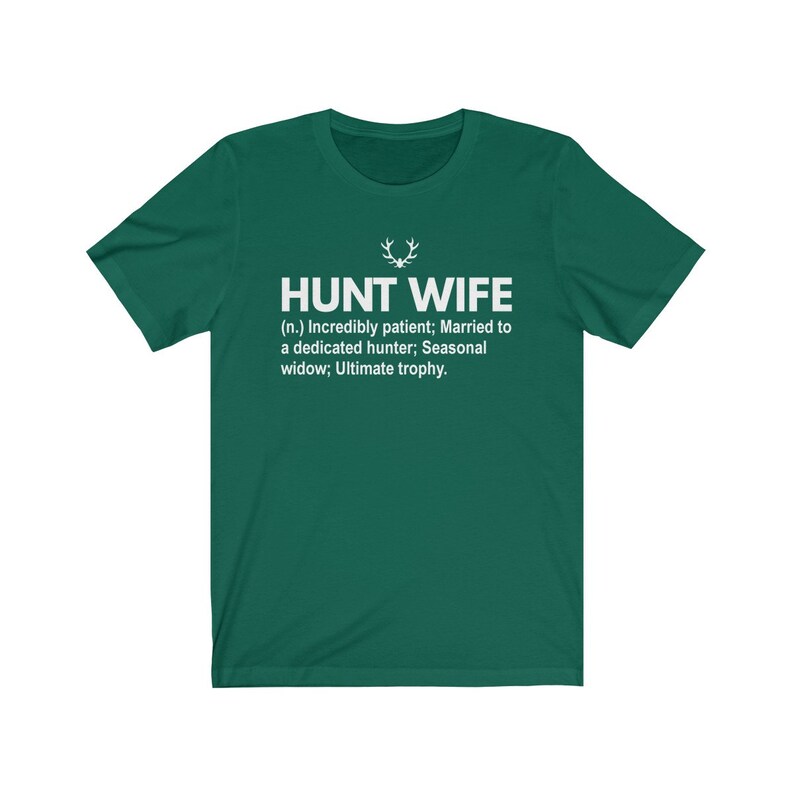 May include: A green t-shirt with white text that reads "HUNT WIFE (n.) Incredibly patient; Married to a dedicated hunter; Seasonal widow; Ultimate trophy."