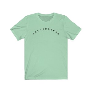 May include: A light green t-shirt with the text "SALVADORENA" printed in black on the front.