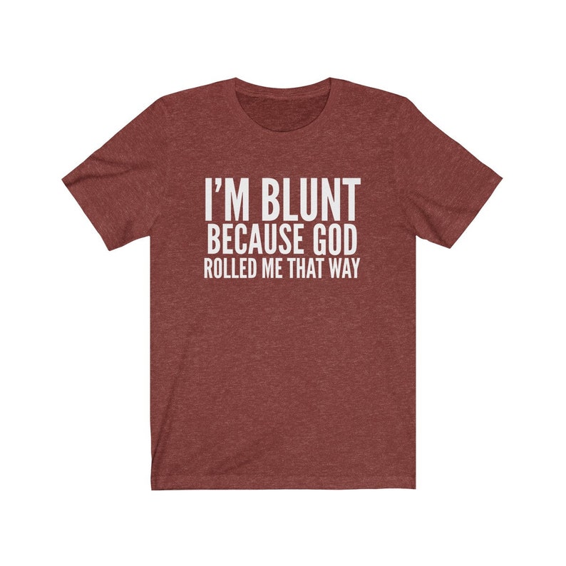 May include: Maroon t-shirt with the text "I'M BLUNT BECAUSE GOD ROLLED ME THAT WAY" in white block letters. The shirt has short sleeves and a crew neck. The fabric has a heathered texture.