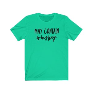 May include: A bright green t-shirt with the phrase "MAY CONTAIN whiskey" printed in black cursive lettering. The shirt has short sleeves and a crew neck.
