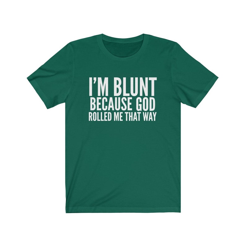 May include: A green t-shirt with the white text "I'M BLUNT BECAUSE GOD ROLLED ME THAT WAY." The shirt has short sleeves and a crew neck. The text is centered on the front of the shirt.