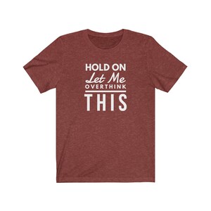 May include: Red heather t-shirt with white text that reads "Hold On Let Me Overthink This".