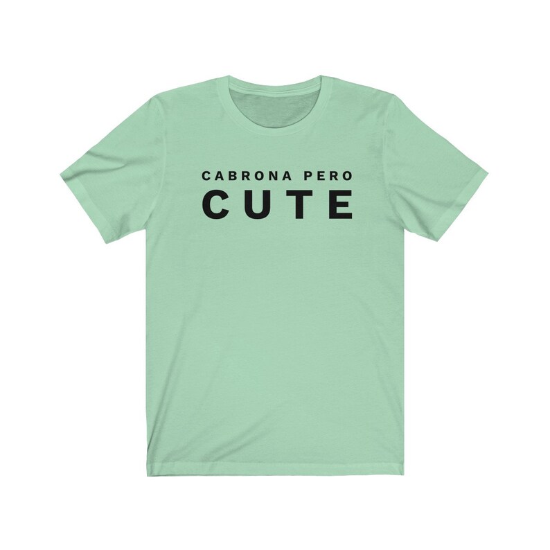 May include: A light green t-shirt with the text "Cabrona Pero Cute" printed in black.
