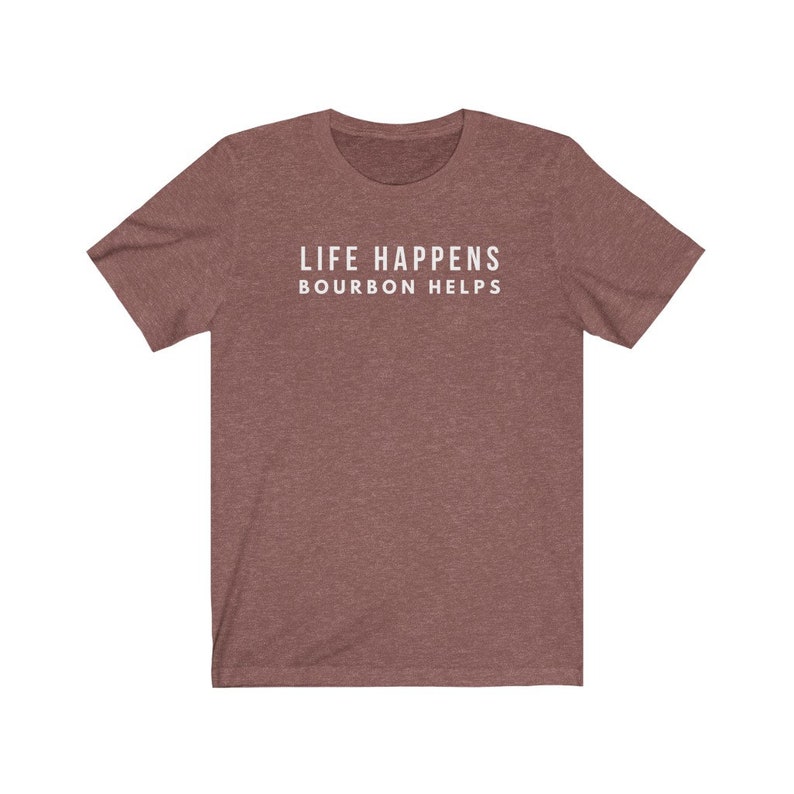 May include: A heather brown t-shirt with the text "LIFE HAPPENS BOURBON HELPS" printed in white.
