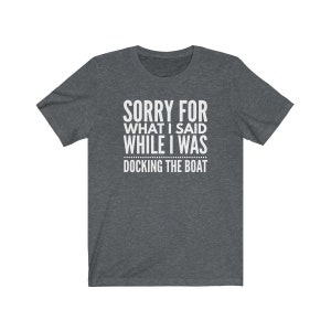 Op de afbeelding: Donkergrijs T-shirt met de witte tekst: "SORRY FOR WHAT I SAID WHILE I WAS DOCKING THE BOAT". Het T-shirt heeft een ronde hals en is waarschijnlijk gemaakt van een zachte stof. Een humoristisch kledingstuk.