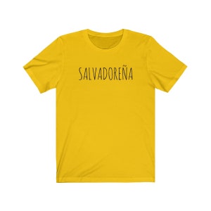 以下が含まれることがあります： 前面に黒い文字で「SALVADORE&Ntilde;A」とプリントされた黄色の半袖Tシャツです。
