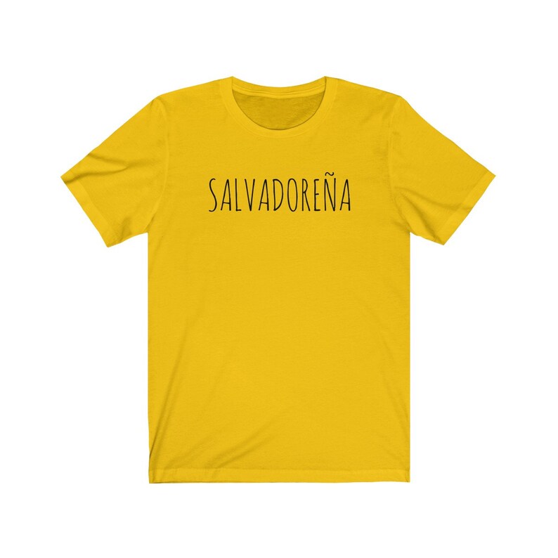 以下が含まれることがあります： 前面に黒い文字で「SALVADORE&Ntilde;A」とプリントされた黄色の半袖Tシャツです。