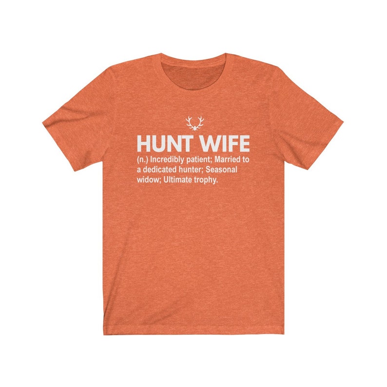 May include: Orange t-shirt with white text that reads "HUNT WIFE (n.) Incredibly patient; Married to a dedicated hunter; Seasonal widow; Ultimate trophy."