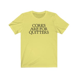 May include: A yellow t-shirt with the text "CORK ARE FOR QUITTERS" printed in black.