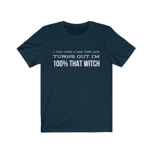 May include: A dark navy blue short-sleeve t-shirt featuring white text printed on the chest that reads: I JUST TOOK A DNA TEST AND TURNS OUT I'M 100% THAT WITCH. The garment has a crew neckline and a standard fit with short sleeves.