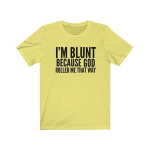 May include: A yellow short-sleeved t-shirt with black text that reads "I'M BLUNT BECAUSE GOD ROLLED ME THAT WAY."
