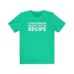 May include: A bright green short-sleeved t-shirt featuring the white text "YOUR OPINION WASN'T IN THE RECIPE" printed in a bold, sans-serif font across the centre of the chest. The garment has a crew neckline and a standard, casual fit.