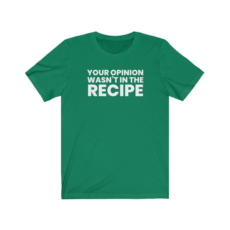 May include: A short-sleeved green t-shirt featuring the white text "YOUR OPINION WASN'T IN THE RECIPE" printed in a bold, sans-serif font across the centre of the chest. The garment has a crew neckline and a standard, straight-cut silhouette.