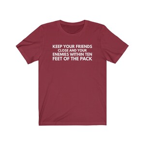 May include: Burgundy t-shirt with white text that reads "Keep your friends close and your enemies within ten feet of the pack."