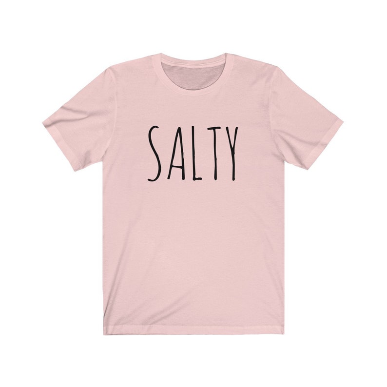 May include: A pink t-shirt with the word "SALTY" printed in black on the front.