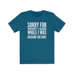 Op de afbeelding: Tealkleurig T-shirt met witte tekst: "SORRY FOR WHAT I SAID WHILE I WAS DOCKING THE BOAT." Het shirt heeft korte mouwen en een ronde hals. De tekst staat in het midden van de voorkant van het shirt.