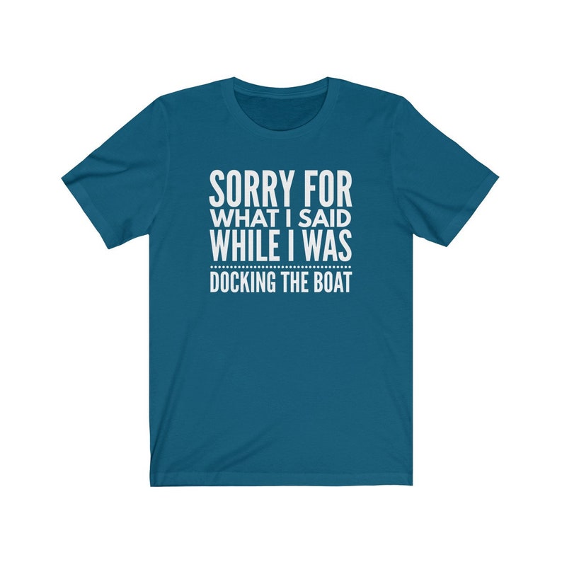 Op de afbeelding: Tealkleurig T-shirt met witte tekst: "SORRY FOR WHAT I SAID WHILE I WAS DOCKING THE BOAT." Het shirt heeft korte mouwen en een ronde hals. De tekst staat in het midden van de voorkant van het shirt.