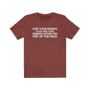 May include: A maroon heather t-shirt with the text "KEEP YOUR FRIENDS CLOSE AND YOUR ENEMIES WITHIN TEN FEET OF THE PACK" printed in white.