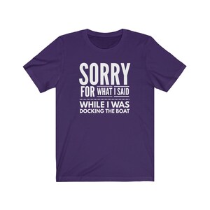 May include: Purple short-sleeved t-shirt with white text that reads "Sorry for what I said while I was docking the boat."