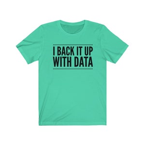 May include: A mint green short-sleeved t-shirt featuring the black text I BACK IT UP WITH DATA centered on the chest. The text is enclosed between two horizontal lines made of small black dots, creating a clean and simple graphic design.