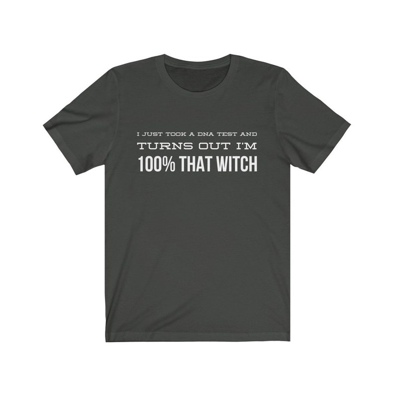 May include: A dark gray short-sleeved t-shirt featuring white text printed on the chest that reads, I JUST TOOK A DNA TEST AND TURNS OUT I'M 100% THAT WITCH. The garment has a crew neckline and a standard fit, displaying clear, bold lettering.