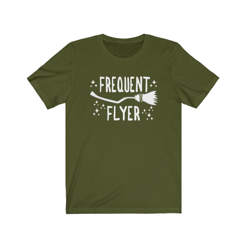 May include: A green t-shirt with a white graphic of a broom and the text "Frequent Flyer" with stars on either side.