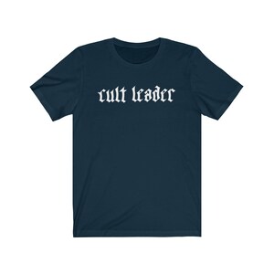 May include: A dark blue t-shirt with the text "cult leader" printed in white on the front.