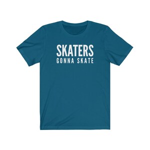 May include: A teal blue t-shirt with white text that reads "SKATERS GONNA SKATE".