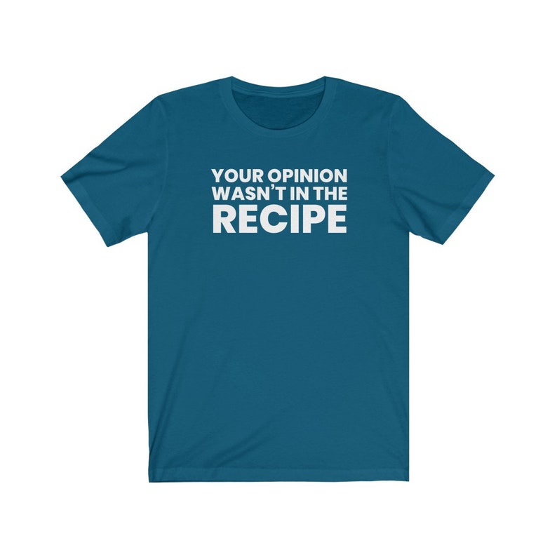 May include: A teal short-sleeved t-shirt featuring the white text "YOUR OPINION WASN'T IN THE RECIPE" printed in a bold, sans-serif font across the centre of the chest. The garment has a crew neckline and a standard, straight-cut silhouette.