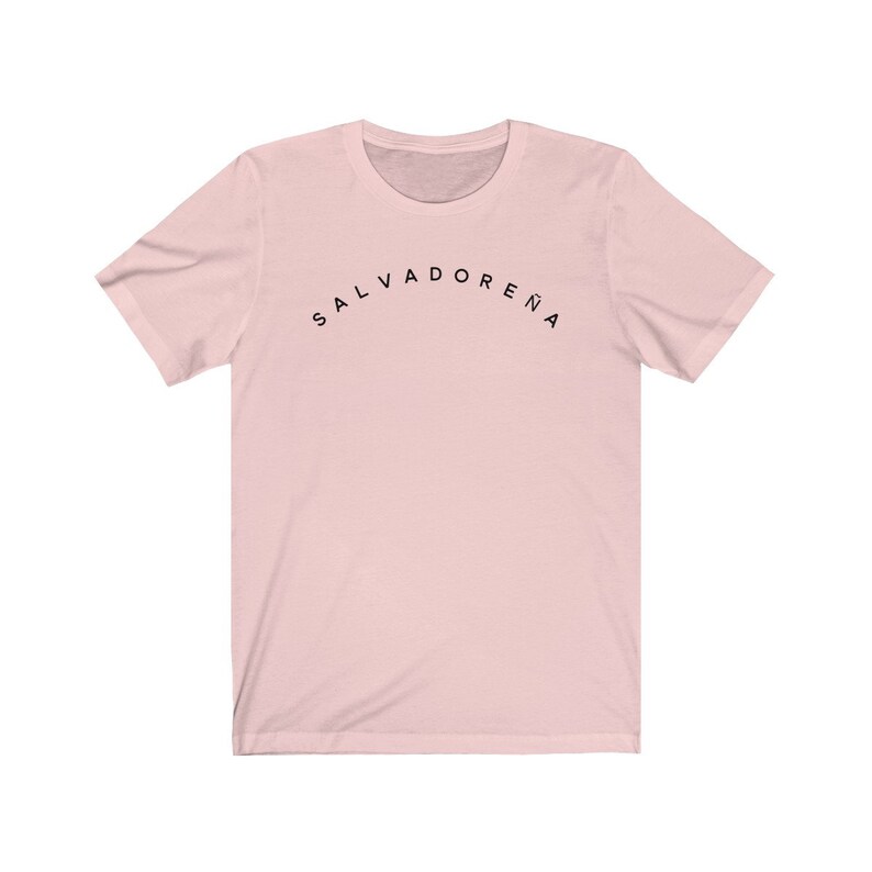 May include: A pink t-shirt with the text "SALVADORENA" printed in black on the front.