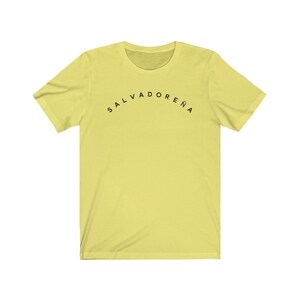 May include: A yellow short-sleeved t-shirt with black text that reads "SALVADORENA" in an arc.