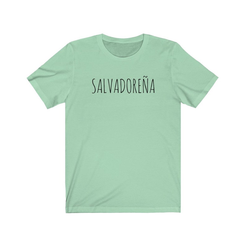 以下が含まれることがあります： 黒で「SALVADORE&Ntilde;A」とプリントされた薄い緑色のTシャツです。