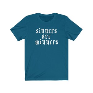 May include: A teal blue t-shirt with the text "sinners are winners" in white gothic font.