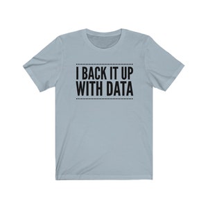 May include: A light blue short-sleeve t-shirt featuring the black text I BACK IT UP WITH DATA centered on the chest. The text is enclosed between two horizontal lines made of small black dots, creating a clean and simple graphic design.