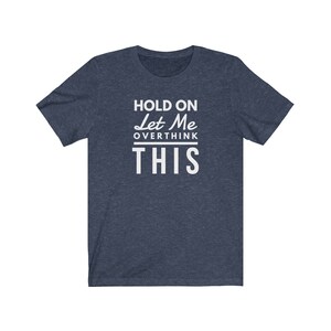 May include: A navy blue t-shirt with white text that reads "Hold On Let Me Overthink This".