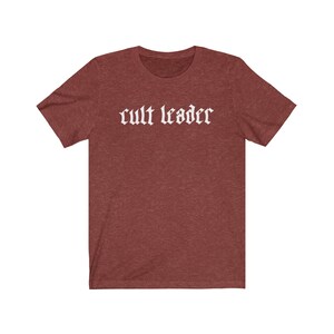 May include: A maroon t-shirt with the text "cult leader" in white gothic font.