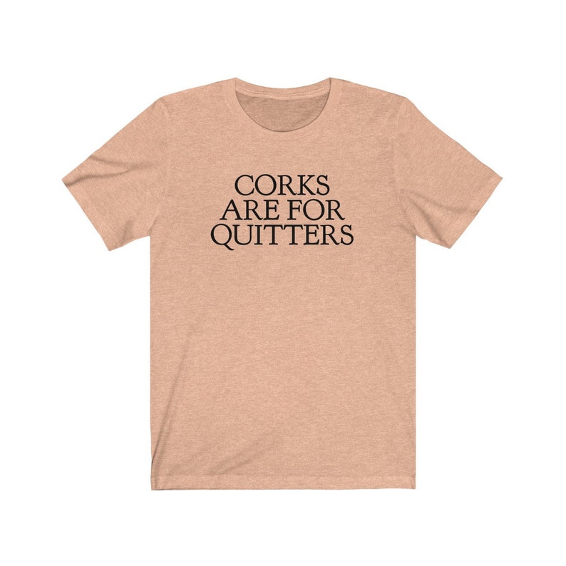 May include: A light peach colored t-shirt with the text "CORK ARE FOR QUITTERS" printed in black.