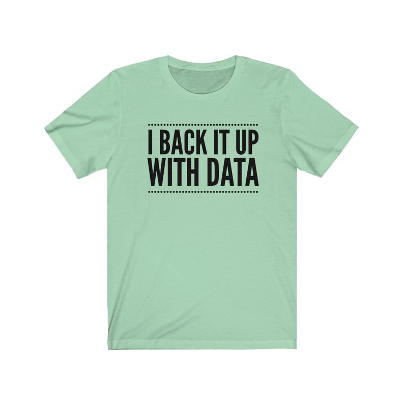 May include: A light mint green short-sleeved t-shirt featuring the black text I BACK IT UP WITH DATA centered on the chest. The text is enclosed between two horizontal lines made of small black dots, creating a clean and simple graphic design.