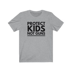 May include: A heather grey t-shirt with black text that reads "PROTECT KIDS NOT GUNS".