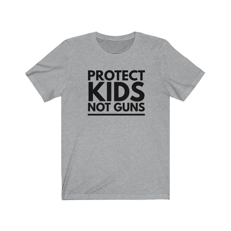 May include: A heather grey t-shirt with black text that reads "PROTECT KIDS NOT GUNS".