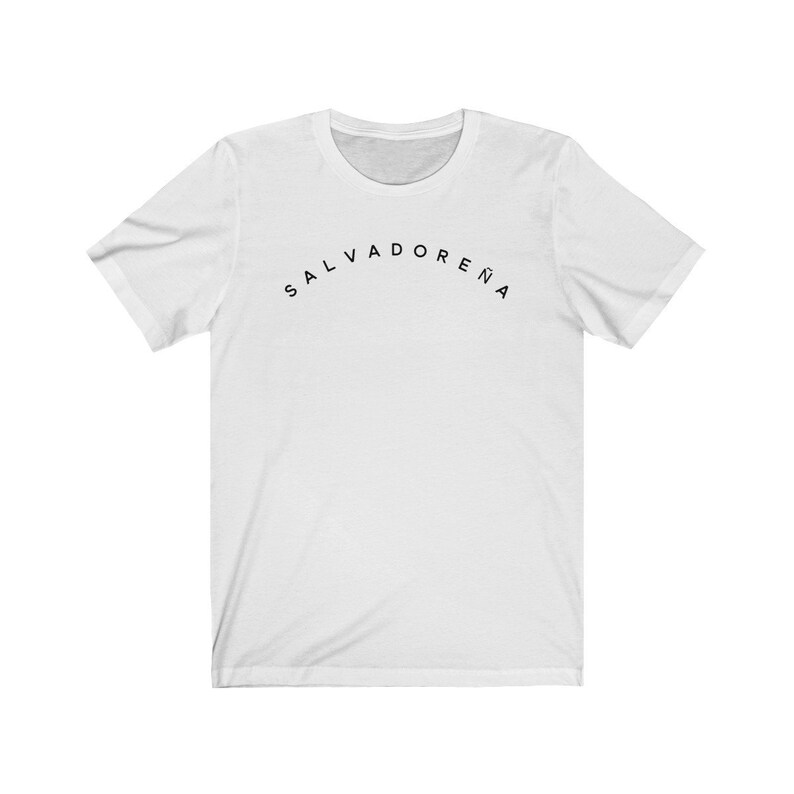 May include: White t-shirt with the text "SALVADORENA" printed in black in an arc across the chest.