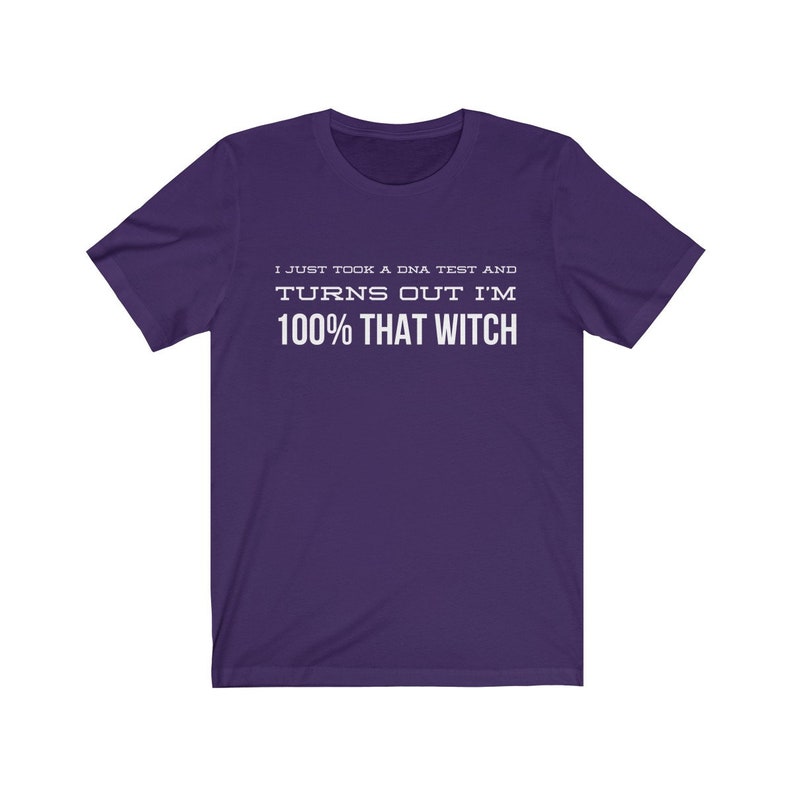 May include: A purple short-sleeved t-shirt featuring white text printed on the chest that reads: I JUST TOOK A DNA TEST AND TURNS OUT I'M 100% THAT WITCH. The garment has a crew neckline and a standard fit, showcasing a solid color design.