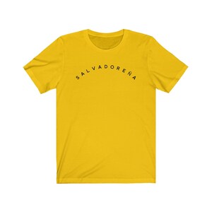 May include: A yellow t-shirt with black text that reads "SALVADORENA" in an arc.