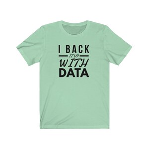 Puede incluir: Una camiseta de manga corta de color verde claro con texto negro impreso en el pecho que dice I BACK IT UP WITH DATA. La prenda tiene un cuello redondo y un corte est&aacute;ndar, mostrando un dise&ntilde;o gr&aacute;fico claro y legible en el centro.